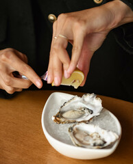 Una persona echando limon a unas ostras de gran calidad