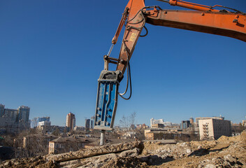 An industrial hydraulic hammer on an excavator boom performs work on dismantling reinforced...