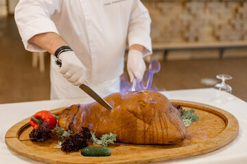 a chef in a restaurant cuts a turkey on the table