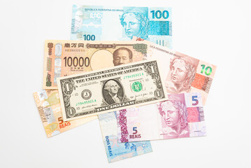 Various banknotes of United States of America, Japan and Brazil scattered and isolated on white background