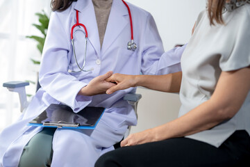 Female doctor holding hand of patient in hospital office giving support