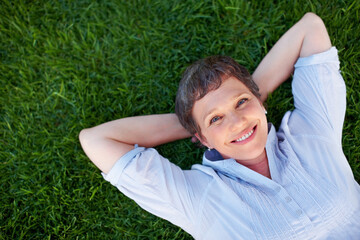 Happy woman, portrait and relax on grass space for comfort, peace and positive mental health. Above, mature person and smile in nature park for summer, freedom and stressless environment for wellness