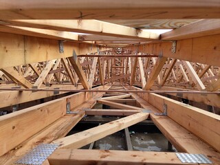 Interior view of a construction site with wooden trusses and metal connector plates, showcasing the...