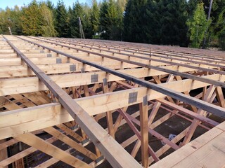 Fototapeta premium Wide-angle view of roof framing with wooden beams and connector plates, capturing the scale and structure under a clear sky
