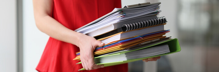Secretary carries stack of folders with accounting materials