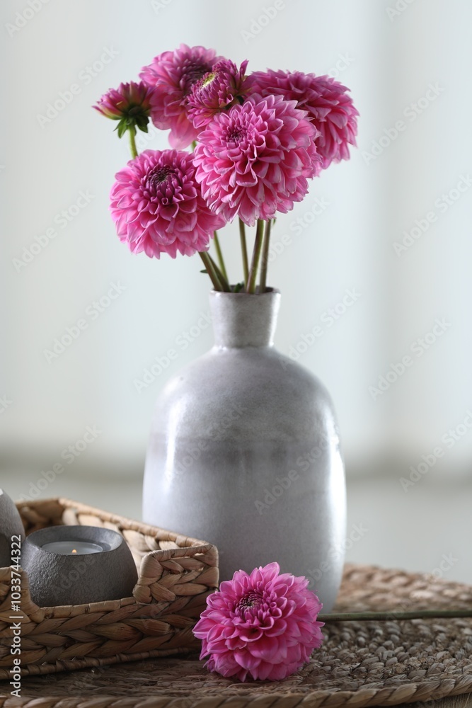 Wall mural Beautiful pink flowers in vase and burning candle on table at home