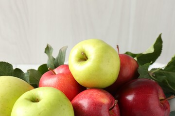 Ripe apples and green leaves on table, closeup