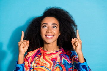 Photo portrait of beautiful curly hair woman in trendy sweatshirt fingers pointing up hot offer isolated on blue color background