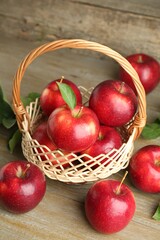 Fresh ripe red apples in wicker basket on wooden table