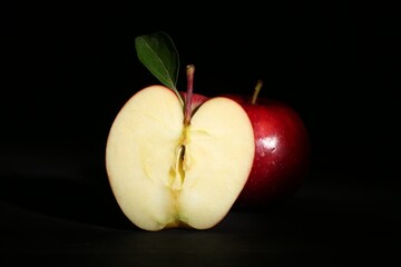 Whole and cut ripe red apples on black background, closeup