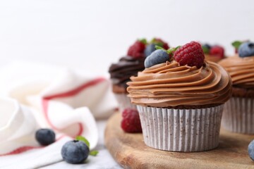 Tasty cupcakes with chocolate cream and berries on table, closeup. Space for text