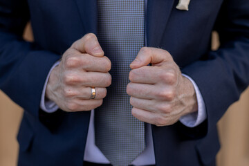 a man in a dark suit and tie with a wedding ring on his finger