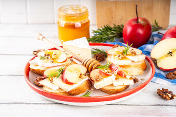 Autumn Apple Brie Crostini with Walnuts and Honey, Fall dinner, Thanksgiving party appetizers idea. Small sandwiches with red apple slices, brie cheese and sweet honey drizzles - Powered by Adobe