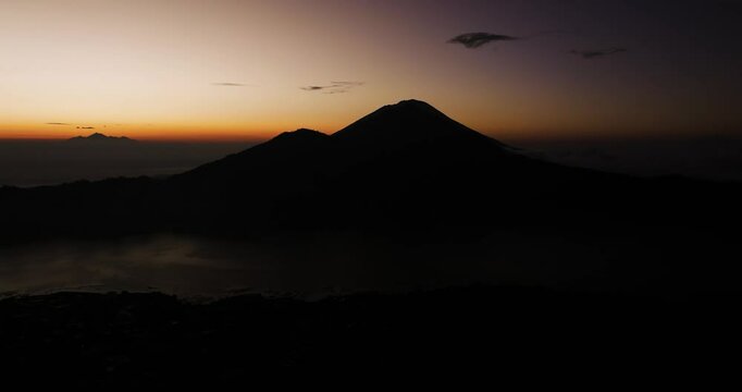Pre-dawn silhouette of Mount Abang with soft light over Bali&rsquo;s volcanic peaks in distance, serene silhouette of mountain against mysterious sky