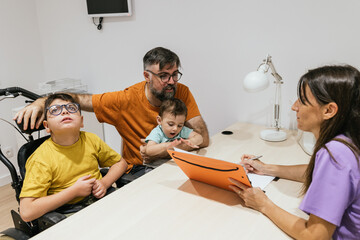 Disabled boy visiting doctor with family for medical consultation
