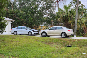 Dented car damaged after traffic accident parked on private home driveway