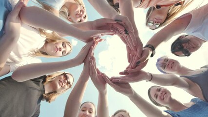 Young schoolchildren join hands in a circle against the backdrop of a summer sky.