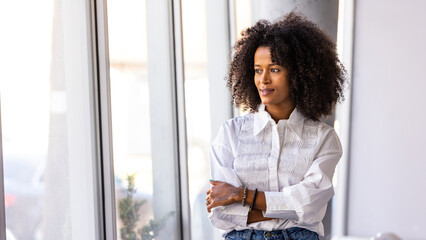 Confident Woman Standing Near Window in Bright Office Setting