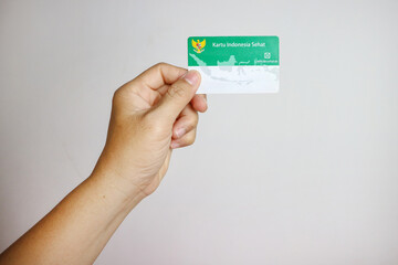Hand holding Indonesian Government Health Insurance Card or (Kartu BPJS Kesehatan) isolated on white background, Magelang-Indonesia, 16-07-2023