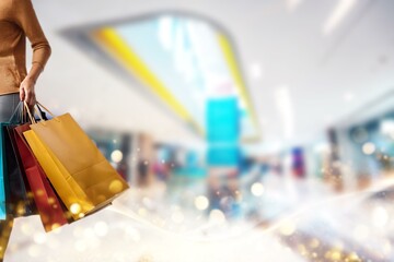 A person in a shopping mall holds colorful shopping bags.