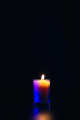 Burning candle on black background with backlight. Memorial Day.