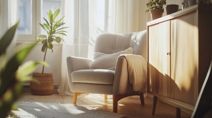Fototapeta premium A cozy Scandinavian-inspired interior with a light wooden cabinet, a plush armchair in warm grey tones, and a potted plant in the corner, all bathed in natural sunlight.