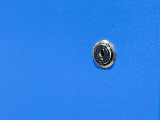 A close-up view of a silver lock on a blue locker in a brightly lit room