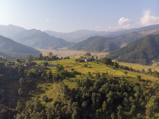 A serene aerial view of a mountainous landscape with scattered houses and lush greenery.