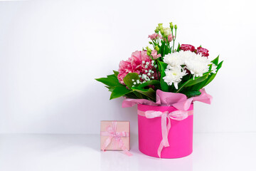 Big beautiful bouquet of  various natural flowers in a pink box near gift. White background.