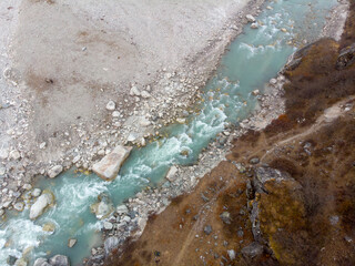 Aerial view of a turquoise river flowing through rocky terrain.