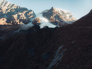 A breathtaking view of a snow-capped mountain range with rocky slopes and a glacier.