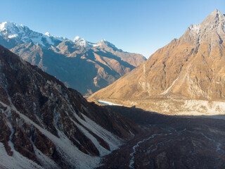 A breathtaking view of snow-capped mountains and a serene valley under a clear blue sky.