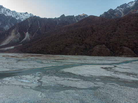 A serene river flowing through a barren, rocky landscape bordered by rugged mountains.