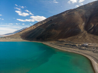 A serene lakeside landscape with crystal clear blue waters adjacent to a mountain