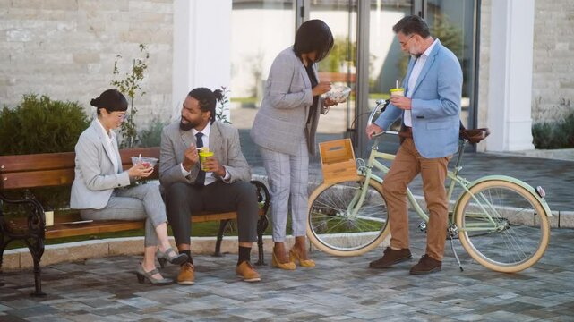 Multiracial business group men and woman taking a break for eating a meal and talking outside the office