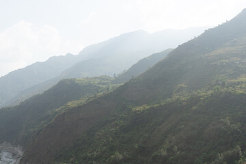 Naklejka premium A hazy mountain landscape with layers of rolling hills and greenery.