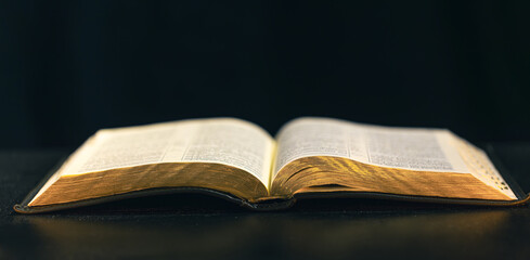 Open Bible on a black background. Religion concept.