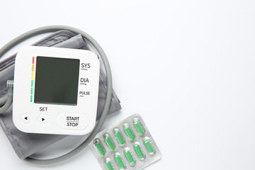 Blood pressure measuring device and pills on white background, top view. Space for text