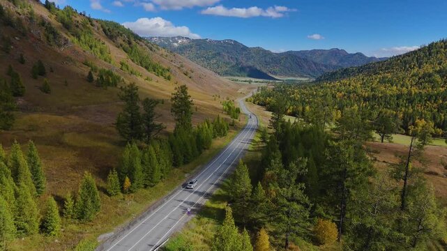 the car is driving along the road in the Altai mountains in autumn