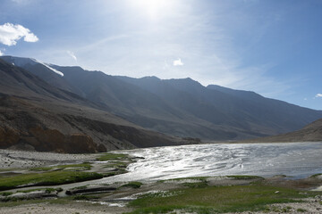 A serene river flowing through a mountainous landscape under a clear sky