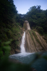 Fototapeta premium A serene waterfall cascading through a lush green forest