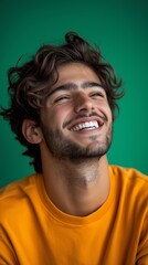 Fototapeta premium Extremely attractive man, dressed in green, who laughs and smiles. a backdrop of vivid, brilliant green.