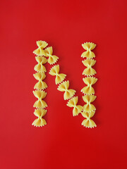 yellow letter N made from pasta on a red background