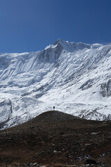 Fototapeta premium A lone hiker stands on a hilltop, gazing at the majestic snowy mountain in the background.