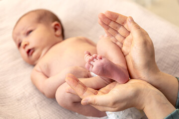 Parent holding in the hands feet of newborn baby. Mom holding baby feet.