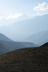 Naklejka premium A serene mountain landscape with layers of misty peaks under a clear sky.