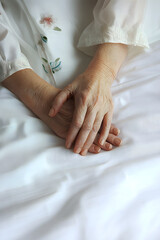 Woman holding senior woman's hand on bed