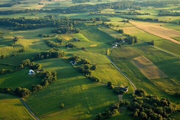 A serene and expansive aerial view of picturesque green fields, winding roads, and quaint homes, exuding the peaceful charm of rural living and natural landscapes.