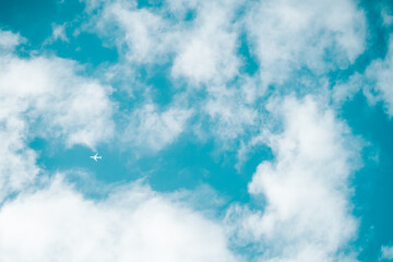 青空に浮かぶ雲と小さな飛行機