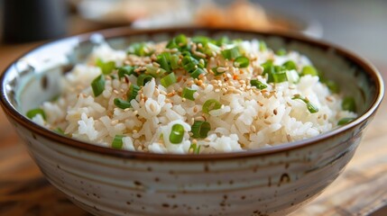 Closeup of a savory steamed rice bowl garnished with fresh green scallions or green onions served in a rustic ceramic dish on a wooden dining table  This simple